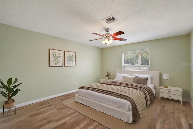 1323 Balboa Ct, The Villages, FL 32159 - bedroom featuring light wood-style floors, baseboards, visible vents, a ceiling fan, and a textured ceiling