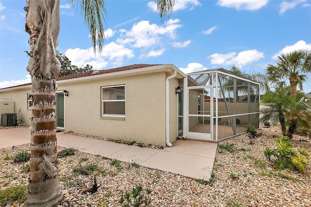1323 Balboa Ct, The Villages, FL 32159 - view of property exterior featuring a patio, central AC, stucco siding, and glass enclosure