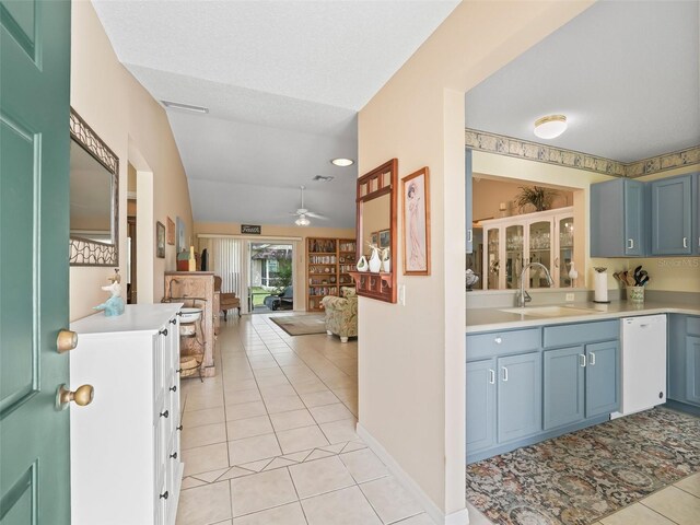kitchen with light tile patterned floors, dishwasher, a sink, a ceiling fan, and open floor plan