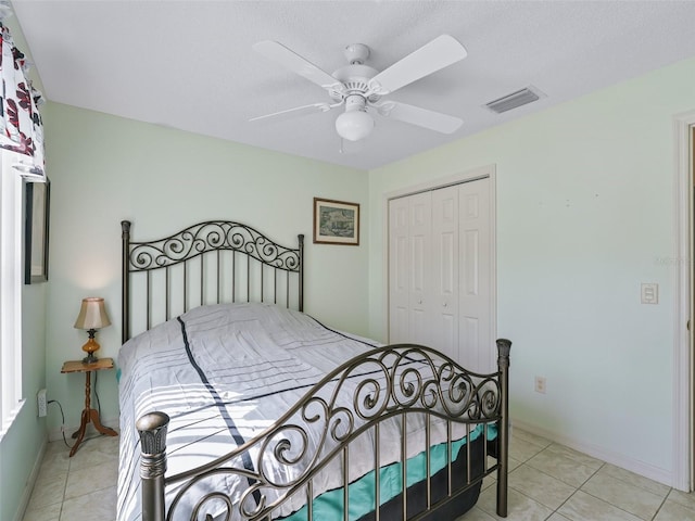 bedroom featuring a closet, ceiling fan, baseboards, visible vents, and light tile patterned flooring