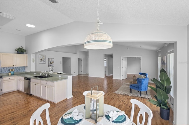 dining space with a textured ceiling, wood finished floors, vaulted ceiling, and arched walkways