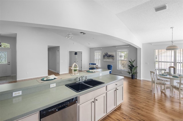 kitchen featuring white cabinets, a sink, visible vents, open floor plan, and dishwasher