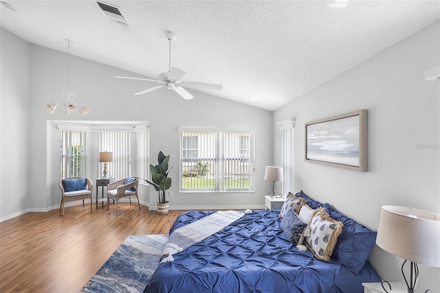 bedroom featuring lofted ceiling, visible vents, a textured ceiling, wood finished floors, and ceiling fan with notable chandelier