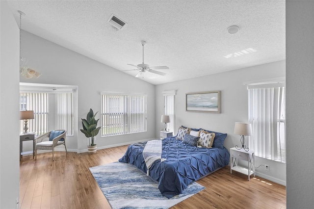 bedroom featuring lofted ceiling, visible vents, baseboards, a textured ceiling, and wood finished floors
