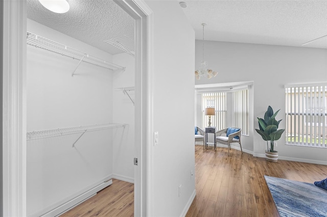 interior space featuring a textured ceiling, an inviting chandelier, hardwood / wood-style flooring, and baseboards