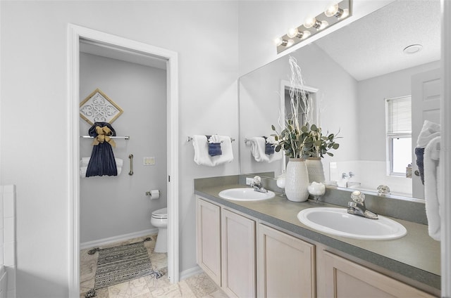 bathroom with a tub, toilet, double vanity, and a sink
