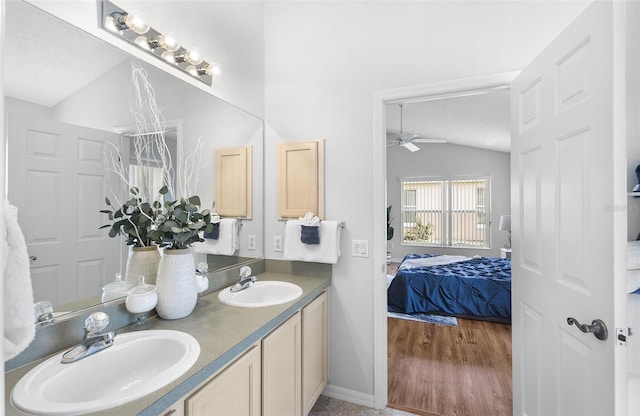 full bath with a sink, ceiling fan, vaulted ceiling, and ensuite bathroom
