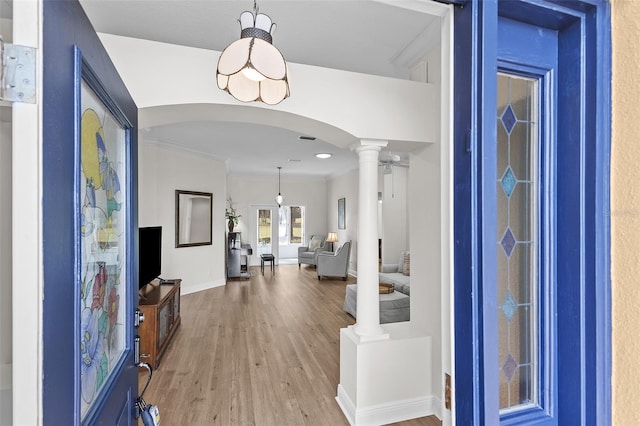 foyer with ornate columns, crown molding, baseboards, arched walkways, and wood finished floors