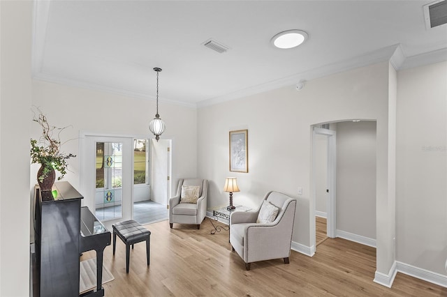 sitting room with crown molding, arched walkways, and visible vents