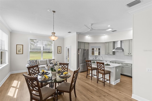dining area with visible vents, light wood-style flooring, and crown molding