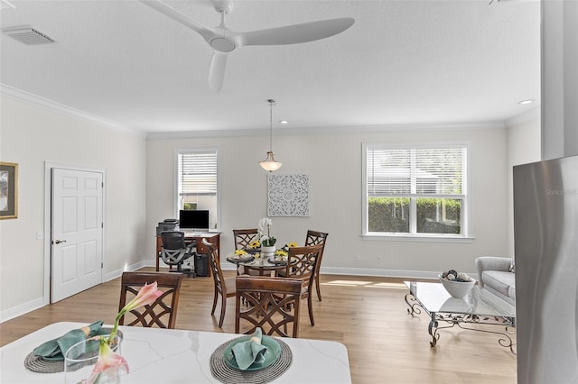 dining room with crown molding, visible vents, wood finished floors, and baseboards