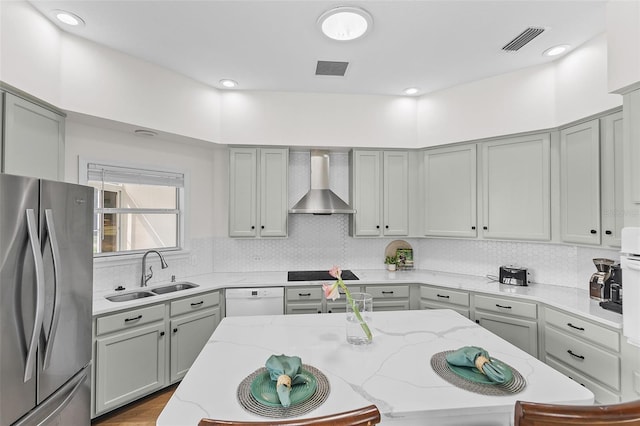 kitchen featuring gray cabinets, a sink, wall chimney exhaust hood, and freestanding refrigerator