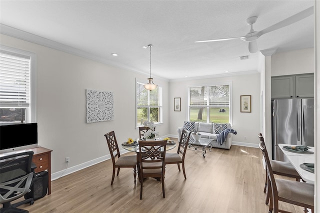 dining space featuring light wood-type flooring, crown molding, and baseboards