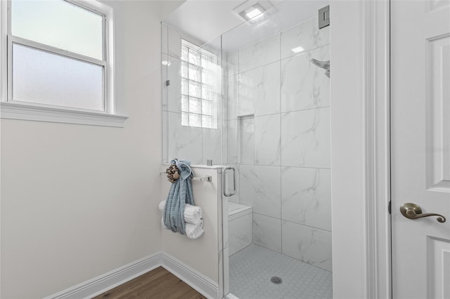 full bathroom featuring a stall shower, a healthy amount of sunlight, and baseboards