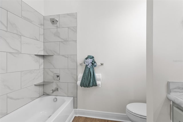 bathroom with baseboards, wood finished floors, toilet, and shower / tub combination