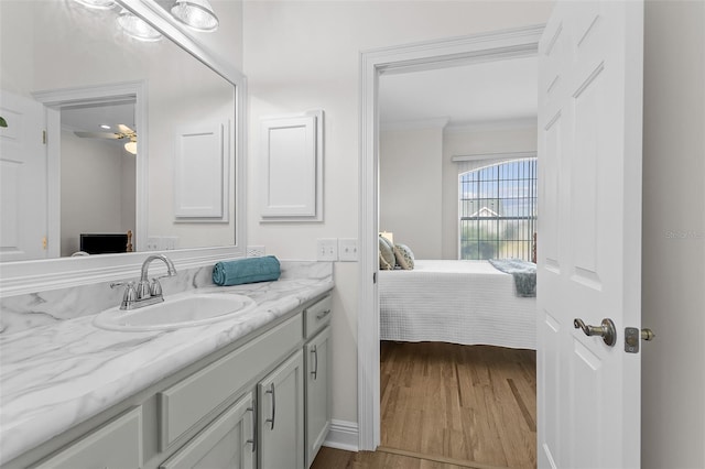 ensuite bathroom featuring wood finished floors, vanity, crown molding, and ensuite bathroom