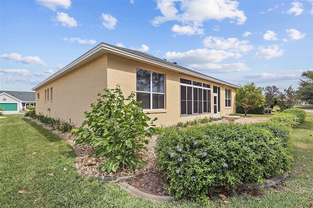 view of side of property with stucco siding and a yard