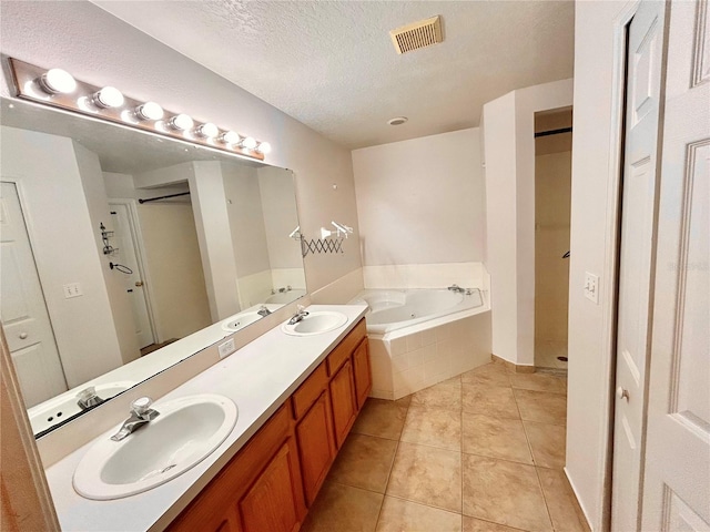 1307 Rain Forest Ln, Minneola, FL 34715 - bathroom featuring a garden tub, double vanity, tile patterned flooring, a textured ceiling, and a walk in shower