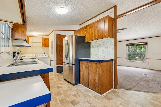 kitchen with a textured ceiling, independent washer and dryer, a sink, freestanding refrigerator, and under cabinet range hood