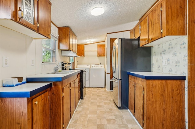kitchen with brown cabinetry, range with electric cooktop, a textured ceiling, washing machine and clothes dryer, and a sink
