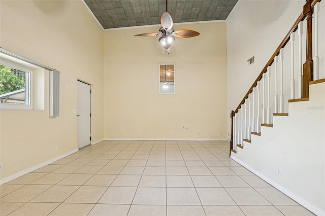 empty room with crown molding, ceiling fan, a towering ceiling, visible vents, and stairway