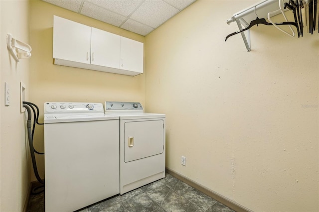 clothes washing area featuring baseboards, independent washer and dryer, and cabinet space