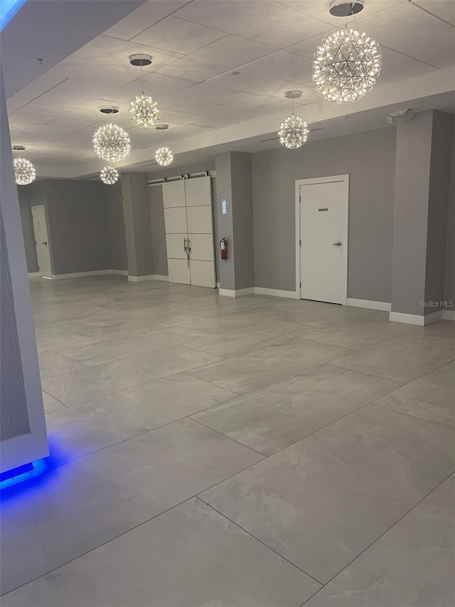 empty room with baseboards, a barn door, and a chandelier