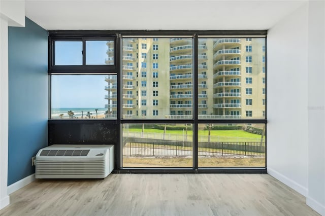 entryway featuring baseboards, a wall mounted AC, wood finished floors, and expansive windows
