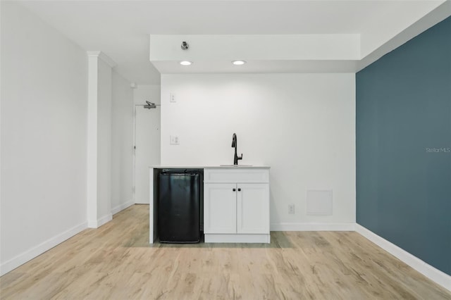 bar featuring light wood-type flooring, a sink, baseboards, and recessed lighting