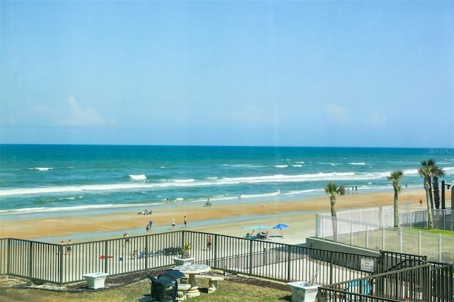 water view featuring fence and a beach view