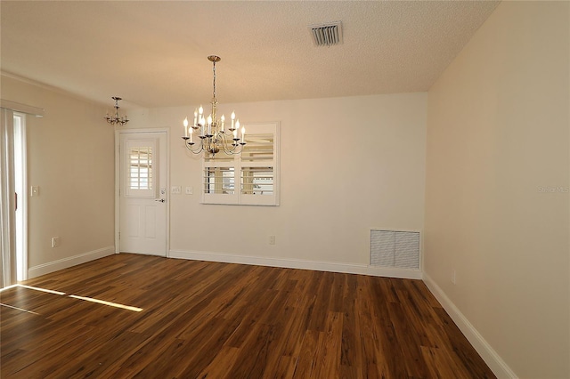 unfurnished dining area with baseboards, a notable chandelier, dark wood-type flooring, and visible vents