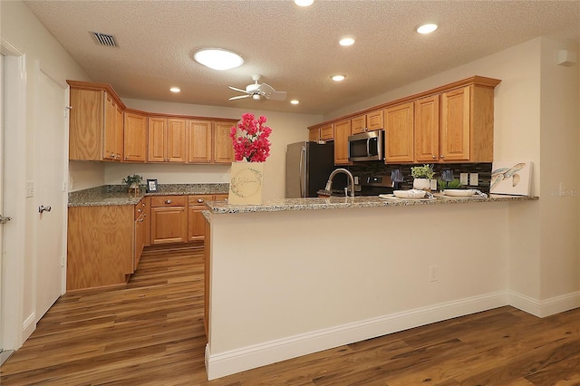 kitchen featuring visible vents, a peninsula, wood finished floors, recessed lighting, and appliances with stainless steel finishes