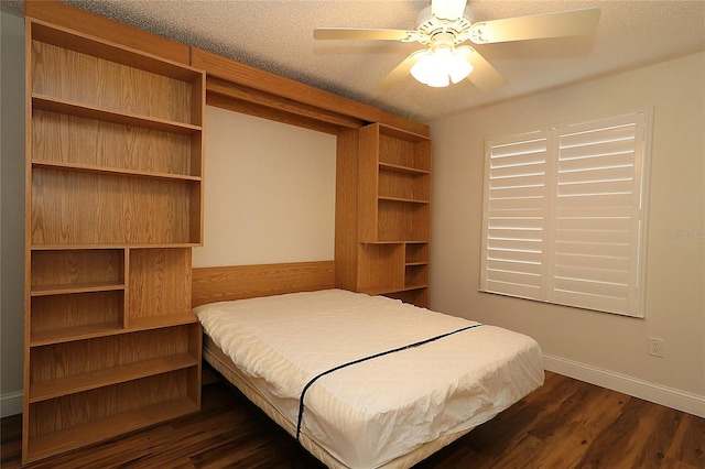 bedroom with dark wood-type flooring, a textured ceiling, baseboards, and ceiling fan