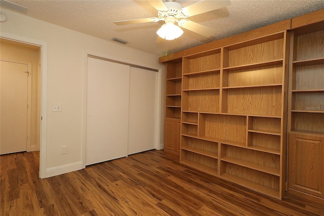 unfurnished bedroom with visible vents, a closet, dark wood-style floors, a textured ceiling, and a ceiling fan