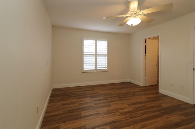 unfurnished room featuring baseboards, dark wood-style flooring, and ceiling fan