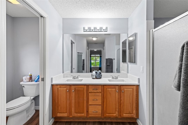 2139 Kaylee Dr, The Villages, FL 32162 - bathroom featuring toilet, double vanity, a shower stall, wood finished floors, and a textured ceiling