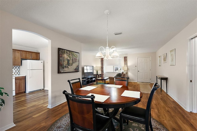 518 Alcazar Ct, The Villages, FL 32159 - dining area with visible vents, a chandelier, dark wood-style floors, baseboards, and arched walkways