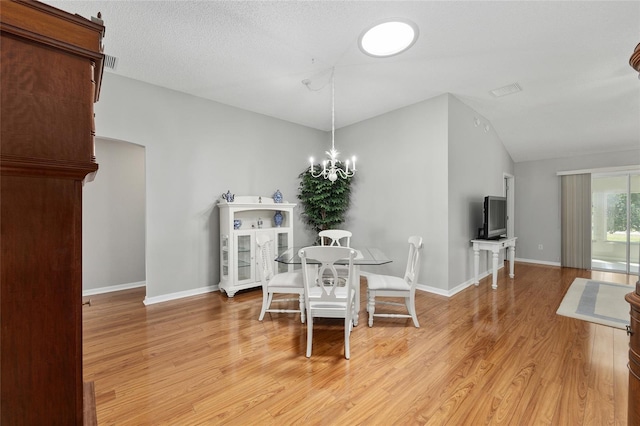 dining area featuring light wood-style floors, vaulted ceiling, baseboards, visible vents, and a notable chandelier
