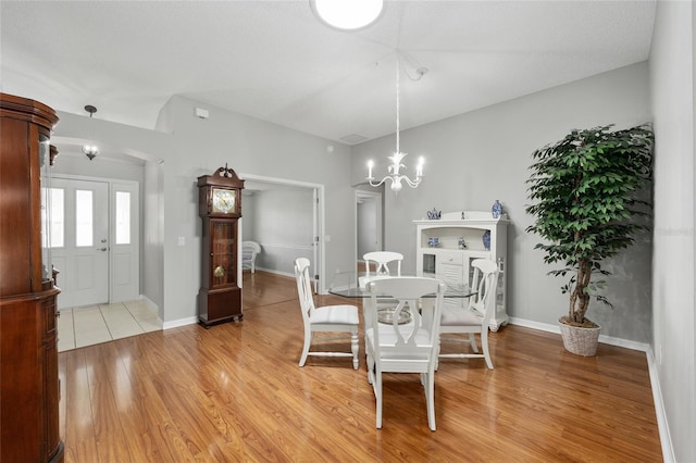dining space with an inviting chandelier, baseboards, and light wood-type flooring