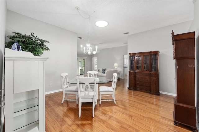 dining area featuring baseboards, visible vents, an inviting chandelier, and light wood finished floors