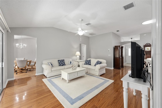 living room with visible vents, light wood-type flooring, a textured ceiling, and vaulted ceiling