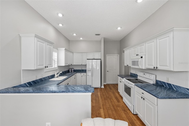 kitchen featuring tasteful backsplash, dark countertops, white appliances, and white cabinetry