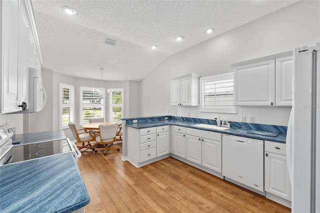 kitchen with white appliances, a textured ceiling, white cabinetry, visible vents, and a peninsula