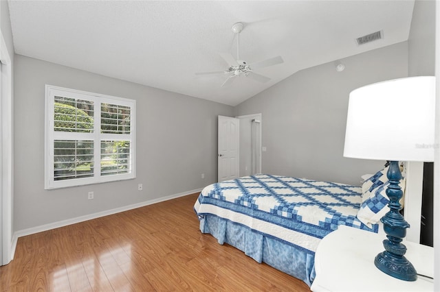 bedroom featuring wood finished floors, a ceiling fan, visible vents, baseboards, and lofted ceiling