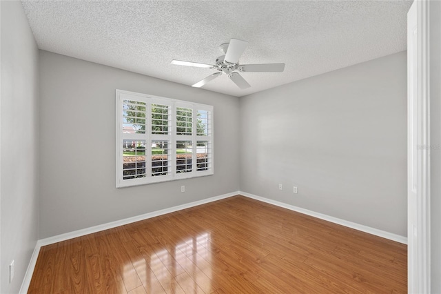unfurnished room featuring a ceiling fan, baseboards, wood finished floors, and a textured ceiling