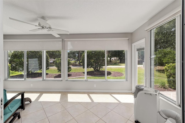 unfurnished sunroom with tile patterned floors, baseboards, and a ceiling fan