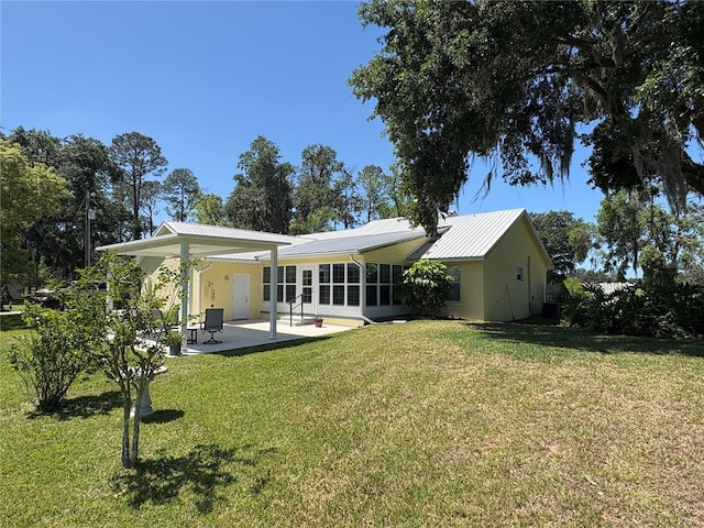 rear view of house with a yard, a patio, and metal roof