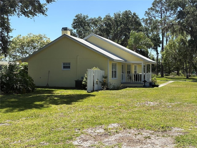 view of home's exterior with central air condition unit, a yard, covered porch, and a chimney
