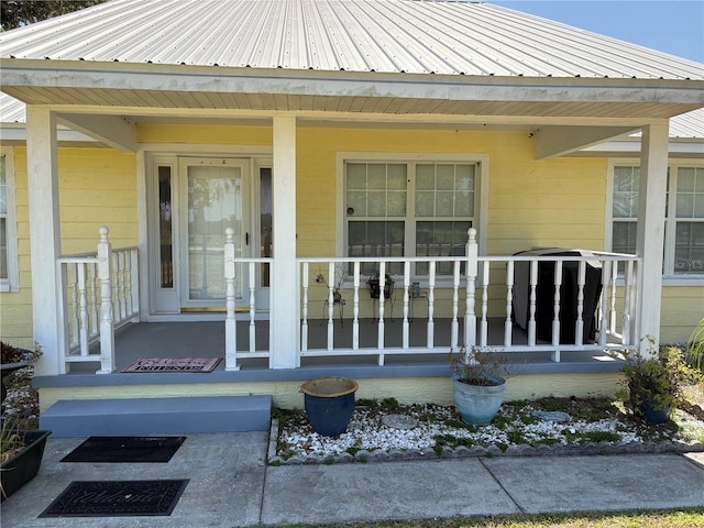 view of exterior entry featuring a porch and metal roof