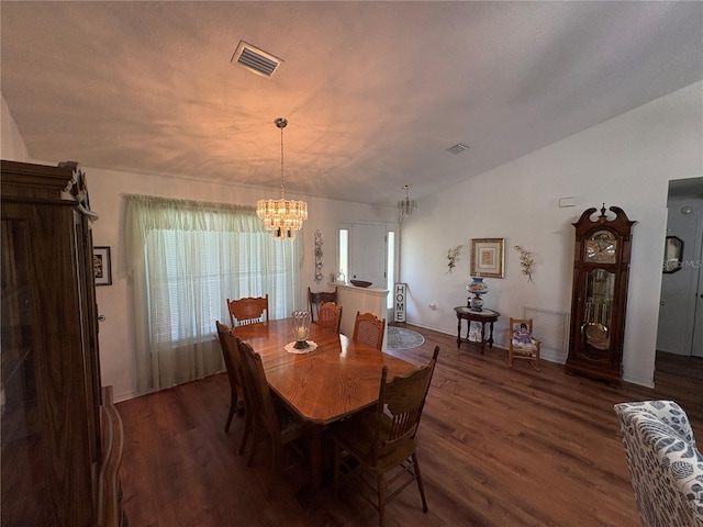 dining area with visible vents, wood finished floors, a notable chandelier, and vaulted ceiling